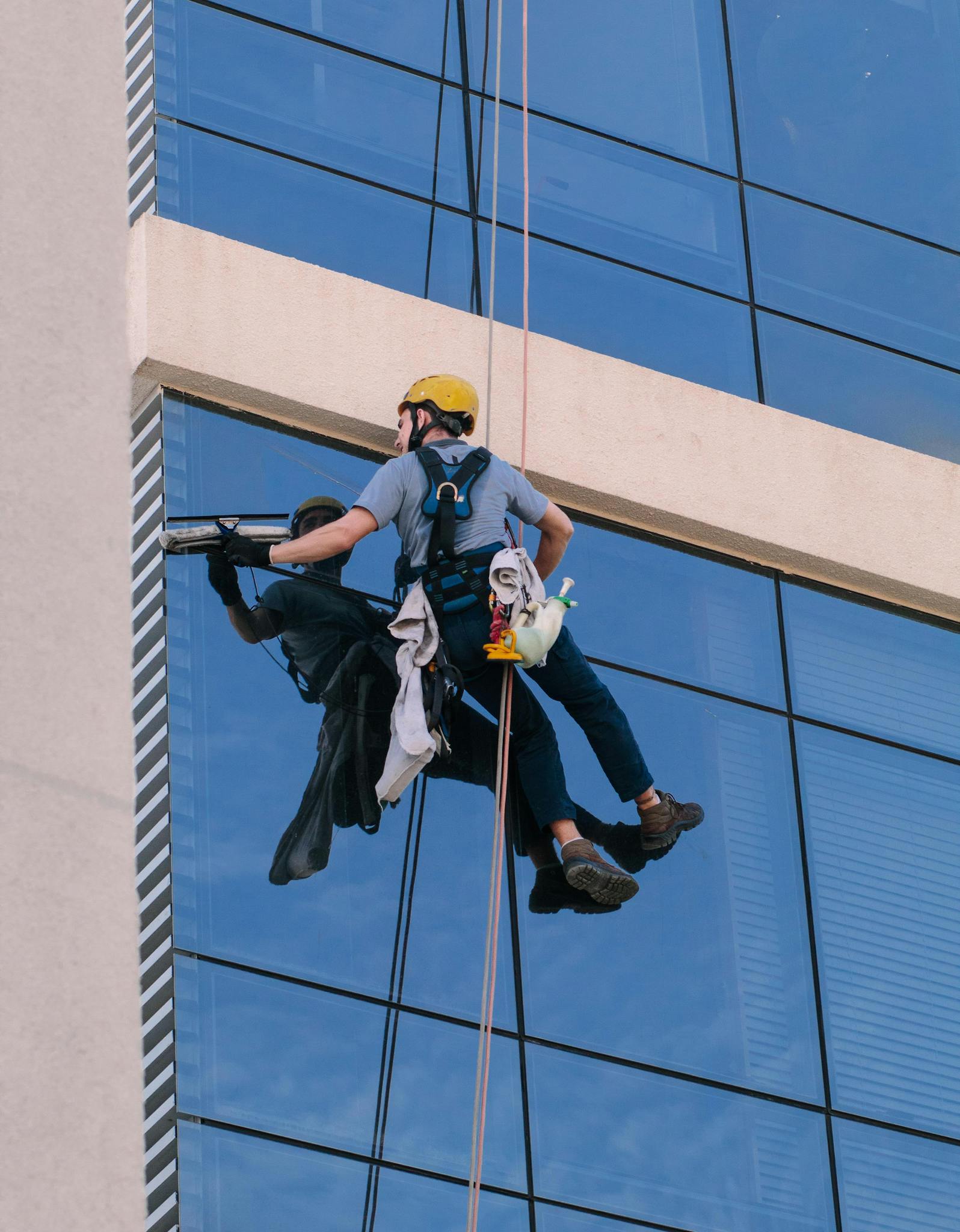 A Man Cleaning Windows Hanging in a Rope